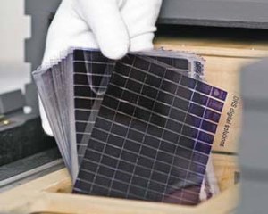 Gloved hand loading a batch of microfiche into the anti-static hopper